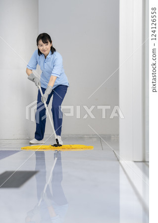 Image of building cleaning: A female cleaning staff member in her 50s mopping the floor 124126558