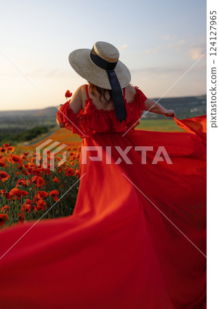 Woman poppy field red dress hat. Happy woman in a long red dress in a beautiful large poppy field. Blond stands with her back posing on a large field of red poppies. Woman poppy field red dress hat. Happy woman in a long red dress in a beautiful large poppy field. Blond stands with her back posing on a large field of red poppies. 124127965
