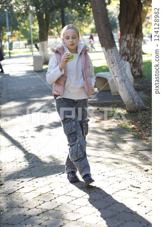 Cute kid holding green apple. Young girl in park, outdoors portrait Cute kid holding green apple. Young girl in park, outdoors portrait 124128982