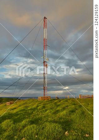 Transmitter tower on a green hill 124129159
