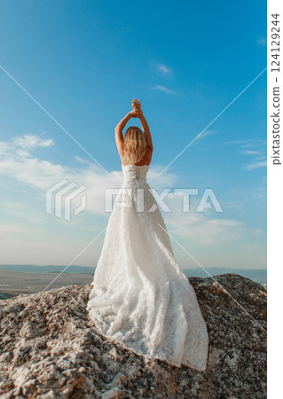 a woman in a white dress, a bride on a mountain with a blue sky. Beautiful nature, freedom, enjoyment of life. High quality photo a woman in a white dress, a bride on a mountain with a blue sky. Beautiful nature, freedom, enjoyment of life. High quality photo 124129244