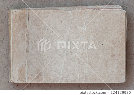 Old worn notebook, vintage texture, aged background, copy space. Aged vintage notebook with worn-out textured cover. Rustic and nostalgic background ideal for retro, antique, literary designs 124129920