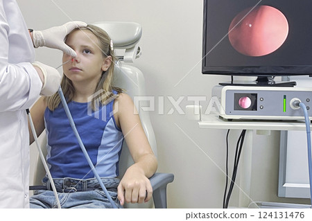Kid girl sitting in clinic while medical examination by nurse. Medical equipment is near them Kid girl sitting in clinic while medical examination by nurse. Medical equipment is near them 124131476