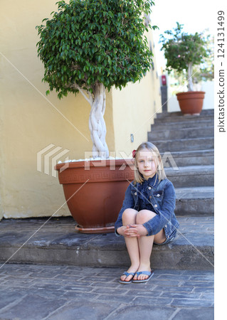 Cute little girl sitting on the stairs outdoors 124131499