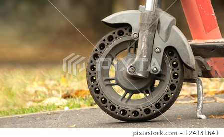 Part of an electric scooter and its front wheel on an autumn alley Part of an electric scooter and its front wheel on an autumn alley 124131641
