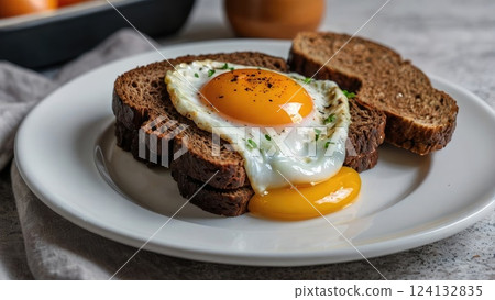 Sandwich of black bread with fried egg on white plate, home food, home breakfast 124132835