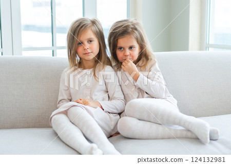Happy family sisterly love. Two funny little twin sisters girls hugging with love care playing together at home indoors. Happy children lifestyle. Identical twin girls hugs. Girls friendship and youth 124132981
