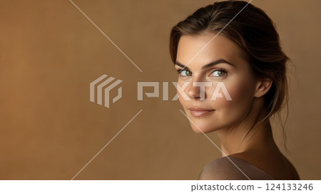 elegant studio portrait of a woman with radiant skin, subtle nude makeup, and serene expression, warm-toned backdrop, negative space on the left for text concept of skincare, beauty, wellness 124133246
