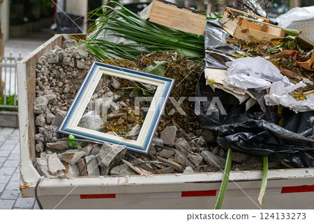 Ornate empty picture frame discarded in a dumpster filled with rubble and debris creating an artistic contrast Ornate empty picture frame discarded in a dumpster filled with rubble and debris creating an artistic contrast 124133273