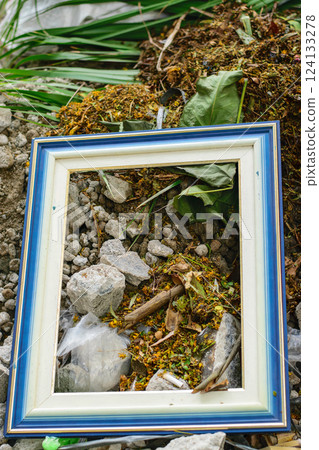 Abandoned empty picture frame lying in debris and rubble symbolizing forgotten memories and urban decay 124133278