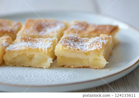 Delicious homemade custard squares sprinkled with icing sugar on plate 124133611