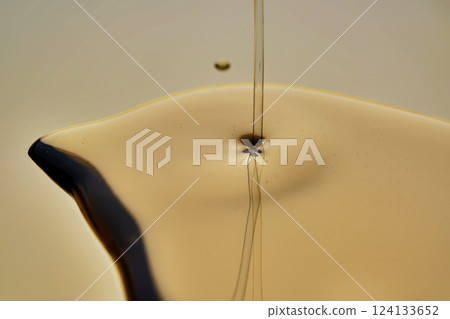Texture of pouring cosmetic oil on a golden background. Texture of pouring cosmetic oil on a golden background. 124133652