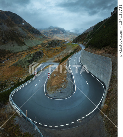 Aerial view of winding mountain road in alpine valley in autumn Aerial view of winding mountain road in alpine valley in autumn 124133731