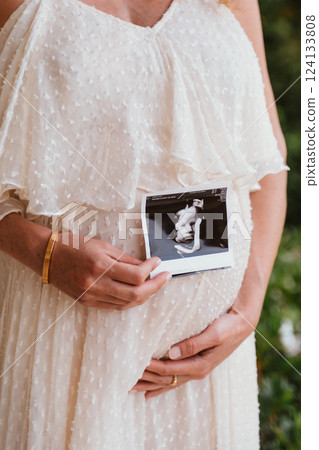 Expectant Mother Holding Ultrasound of Baby Bump 124133808