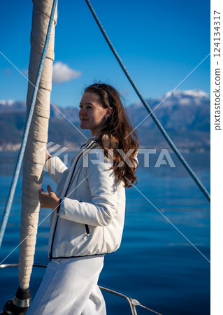 Portrait of young woman on bow of the yacht during sailing in the morning in winter time in Adriatic sea, yacht life and yachting concept 124134317