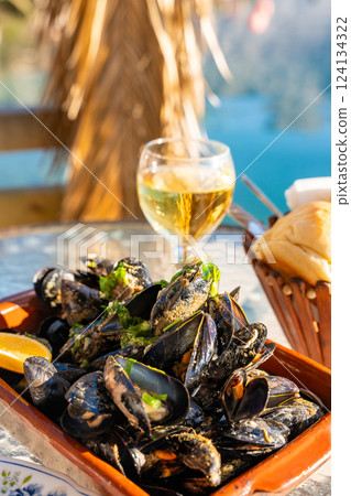 Mussels and white wine in a restaurant with a sea view in oyster farm of Kotor Bay, Montenegro 124134322