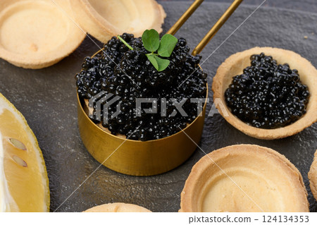Black sturgeon caviar and empty round tartlets on table, top view 124134353