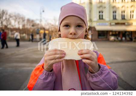 Little girl holding a typical traditional warm waffle or spa waffle in town Karlovy Vary or Carlsbad, Czech Republic Little girl holding a typical traditional warm waffle or spa waffle in town Karlovy Vary or Carlsbad, Czech Republic 124134392