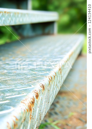Close up of weathered metal steps in outdoor setting. 124134410