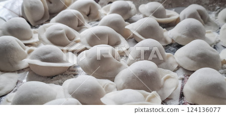 Dumplings rolled in flour. There are a lot of prepared dumplings on the tray for cooking. Dumplings rolled in flour. There are a lot of prepared dumplings on the tray for cooking. 124136077