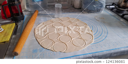Rolled out dough for dumplings. The dough is rolled out and pressed into circles for further preparation of dumplings. 124136081