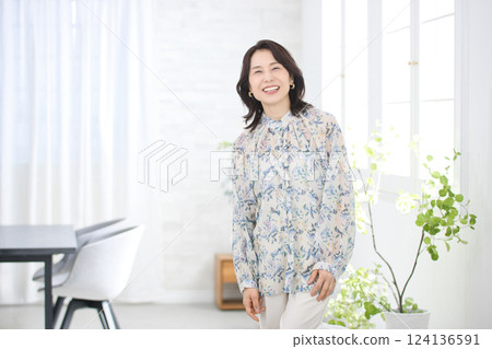 A smiling middle-aged woman wearing a floral blouse 124136591