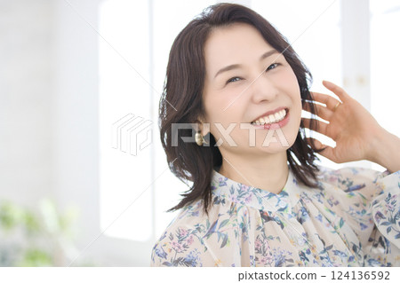 A smiling middle-aged woman wearing a floral blouse A smiling middle-aged woman wearing a floral blouse 124136592