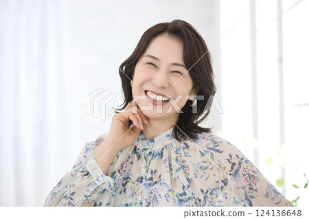 A smiling middle-aged woman wearing a floral blouse 124136648
