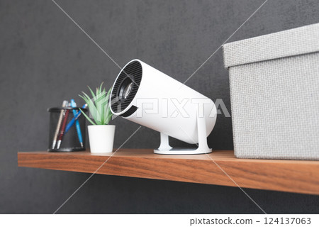 White projector with a lens on shelf 124137063
