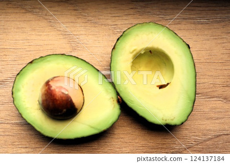 Delicious Fresh Avocado Halves Displayed Neatly on a Rustic Wooden Background Surface Delicious Fresh Avocado Halves Displayed Neatly on a Rustic Wooden Background Surface 124137184