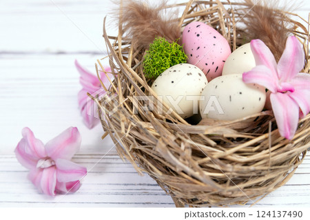 Easter nest with speckled eggs, moss and pink flowers. 124137490