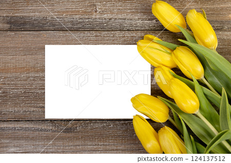 White card and yellow tulips on wooden rustic background. 124137512