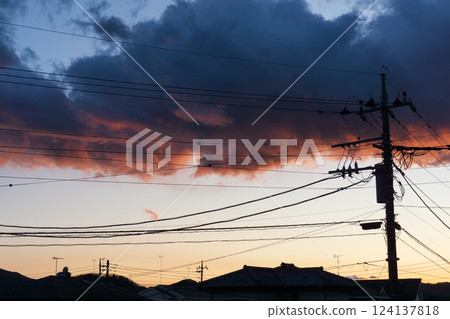 Sunset clouds and the silhouette of utility poles and houses Sunset clouds and the silhouette of utility poles and houses 124137818