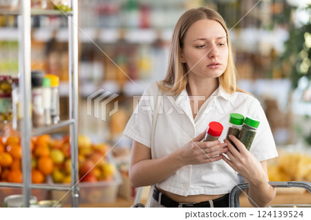 Young woman choosing spices in grocery store Young woman choosing spices in grocery store 124139524