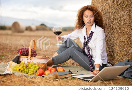 Businesswoman drinking wine and working on laptop near haystack 124139610