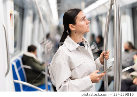 Woman with phone stand in metro carriage. 124139816