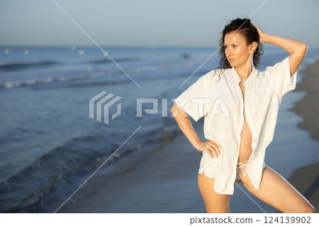 Topless woman in white shirt standing on coast Topless woman in white shirt standing on coast 124139902