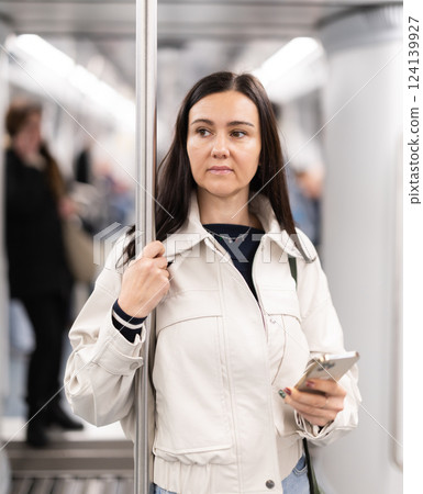 Woman with phone stand in metro carriage. Woman with phone stand in metro carriage. 124139927