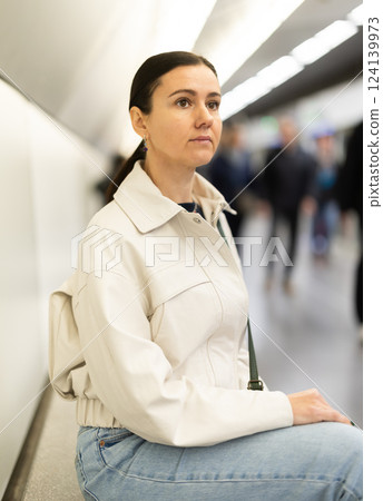 Woman in anticipation of metro train sits on bench at station 124139973