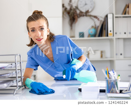 Positive woman cleaner polishing table in office 124140224