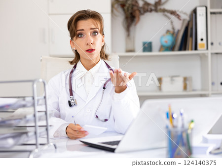 Woman doctor talking and looking at camera inside office 124140375