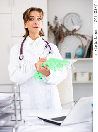 Woman doctor wear white medical uniform and stethoscope with folder of documents 124140377