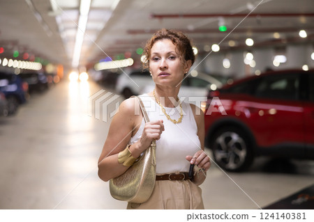 Adult woman stands in parking lot with keys 124140381