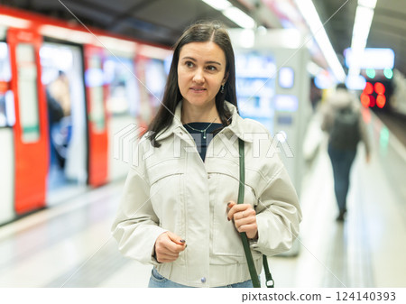 Girl is standing on metro platform station, waiting for transport to arrive 124140393
