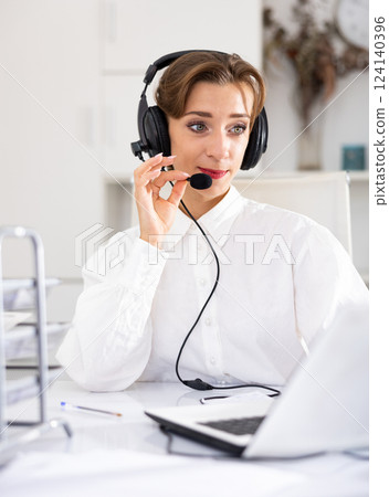 Cheerful woman with headset working in call center 124140396