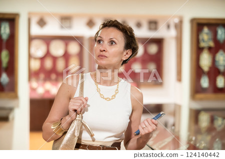 Historical museum - woman with smartphone in her hands looks at an exhibition of medieval sculptures and objects in historical museum 124140442