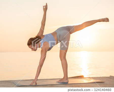 Near sea during sunset, girl performs eka padasana Near sea during sunset, girl performs eka padasana 124140460