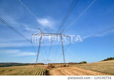 High voltage tower with electric power lines transferring electrical energy through cable wires 124140758