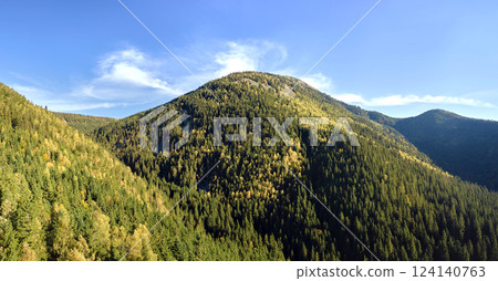 High hills with dark pine woods on autumn bright day. Amazing scenery of wild mountain woodland 124140763