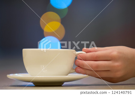 Hand holding white cup of coffee with colorful bokeh steam 124140791